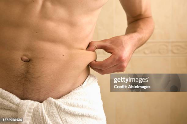 close up of young man pinching his waist - body men close up stock-fotos und bilder