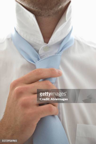 close up of a young man tightening his tie - adjusting blue tie stock-fotos und bilder