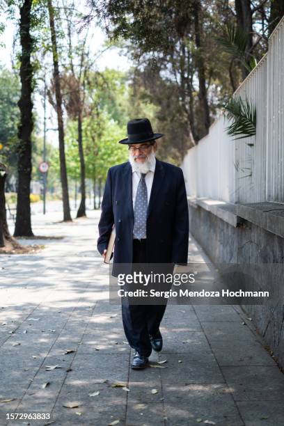 orthodox jewish man holding a large holy text walks down a street in mexico city, mexico - haredi judaism stock pictures, royalty-free photos & images
