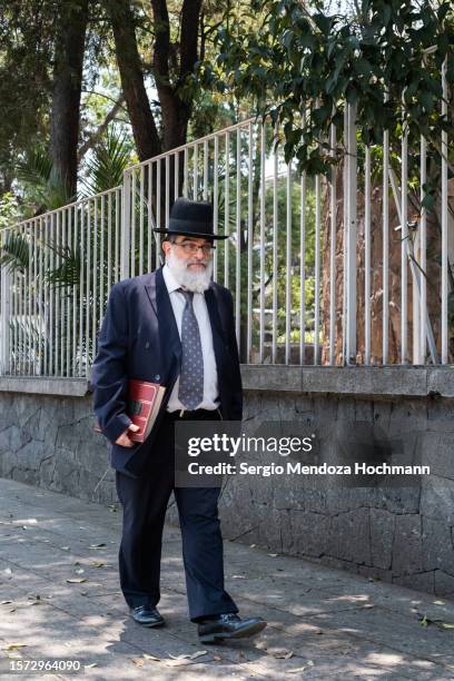 orthodox jewish man holding a large holy text walks down a street in mexico city, mexico - orthodox jew stock pictures, royalty-free photos & images