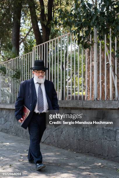 orthodox jewish man holding a large holy text walks down a street in mexico city, mexico - haredi judaism stock pictures, royalty-free photos & images