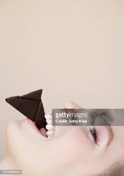 close up profile of beautiful young woman eating chocolate - woman chocolate stock pictures, royalty-free photos & images