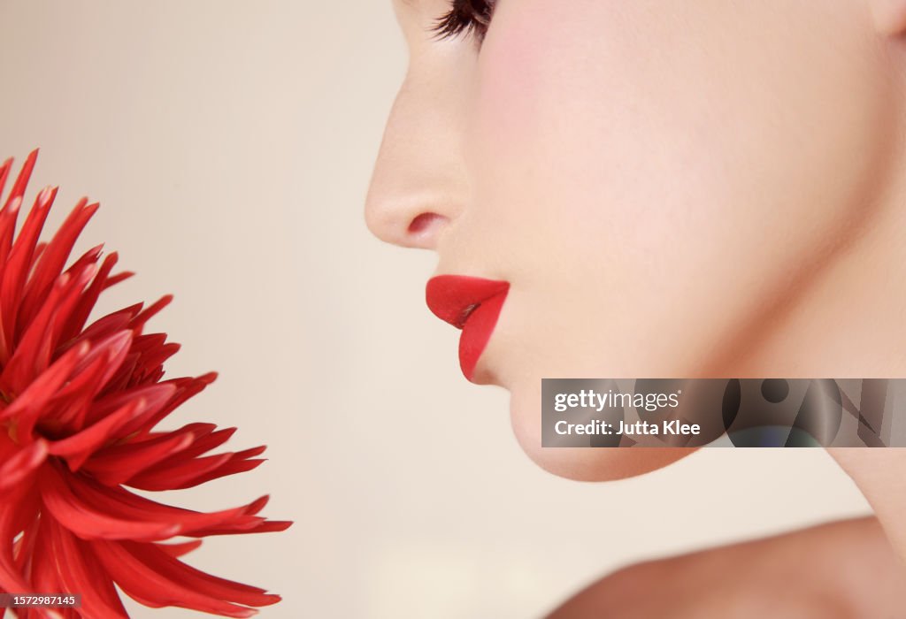 Close up of young beautiful woman inhaling red dahlia