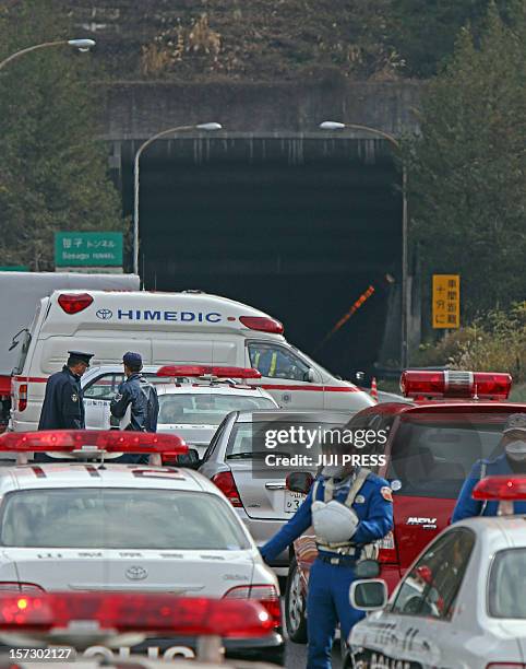 Police and fire workers stand alongside emergency services vehicles outside the entrance of the collapsed Sasago tunnel on the Chuo expressway in...