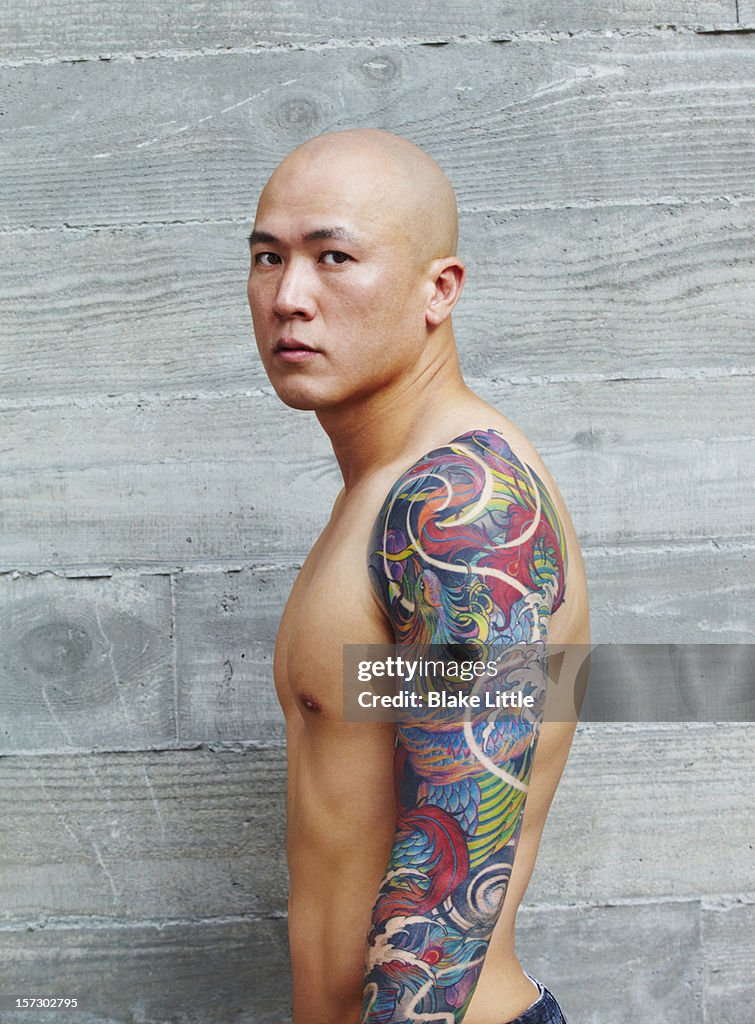 Asian man with arm tattoo.