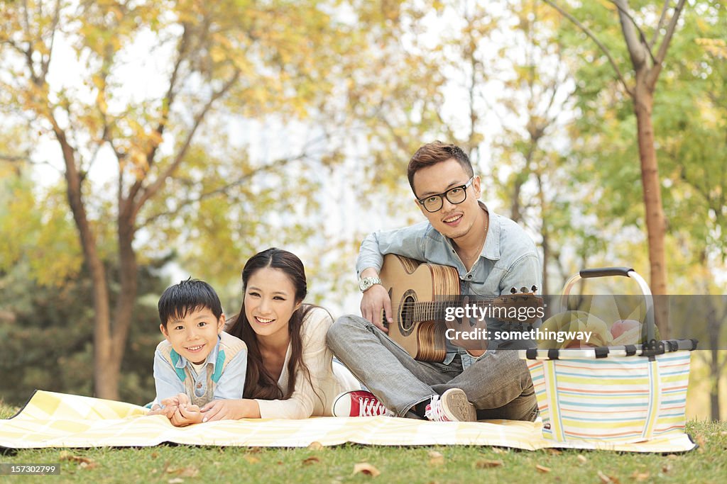 Happy family playing guitar in park