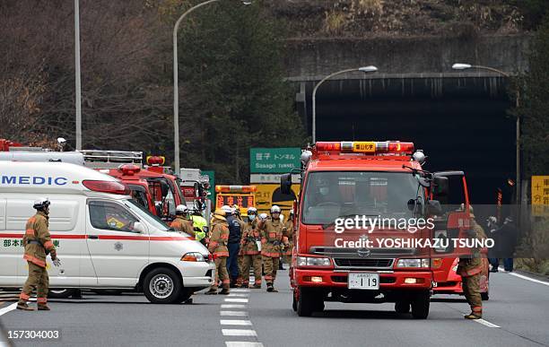 Rescue workers and policeman gather alongside emergency services vehicles on the road leading to the entrance of the collapsed Sasago tunnel on the...