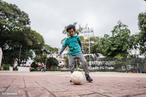 child homeless boy playing soccer outdoors - poor kids playing soccer stock pictures, royalty-free photos & images