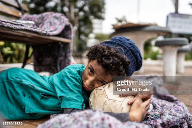 portrait of a child homeless boy lying down on floor outdoors - orphan boy stock pictures, royalty-free photos & images