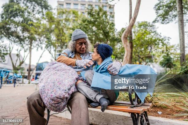 älterer obdachloser spricht mit seinem enkel im freien - bettler stock-fotos und bilder