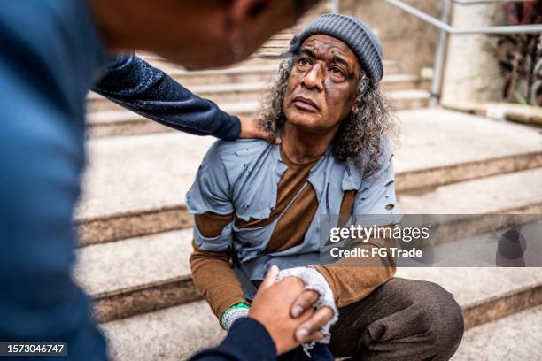 man helping a senior homeless outdoors - homeless person stockfoto's en -beelden