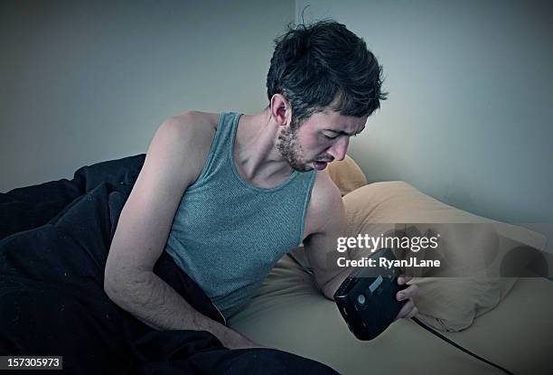 giovane uomo guardare orologio a letto - daylight saving time foto e immagini stock