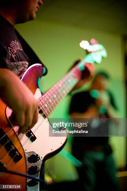 close-up of a musician playing the bass guitar in a band - guitarist band stock pictures, royalty-free photos & images