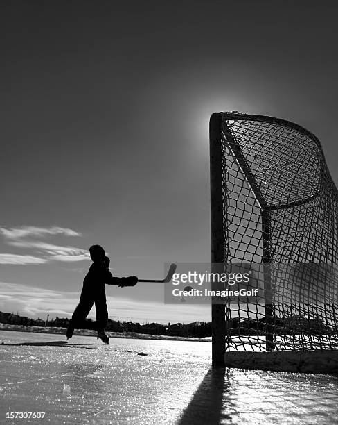 young boy playing outdoor ice hockey - ice hockey stockfoto's en -beelden