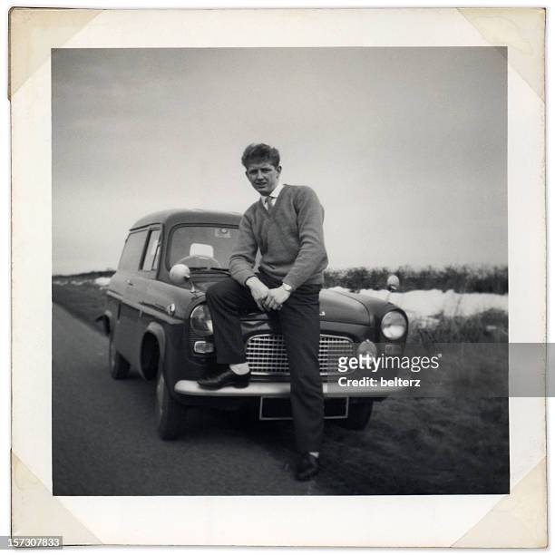 black and white photo of man sitting on vintage car bonnet - non urban scene stock pictures, royalty-free photos & images