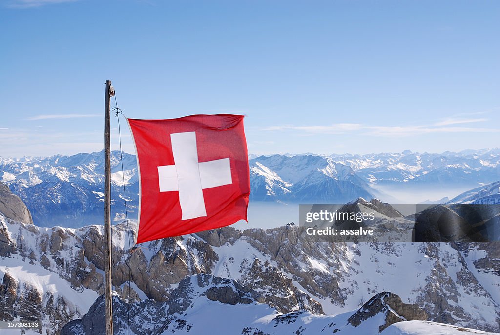 Swiss flag flying over snowy mountains