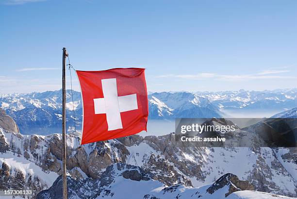 swiss flag flying over snowy mountains - swiss flag stockfoto's en -beelden