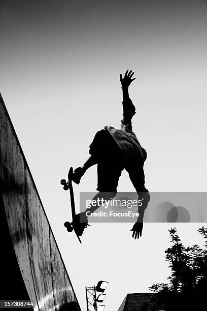 black and white image of man performing a skateboard jump - figure skater stockfoto's en -beelden