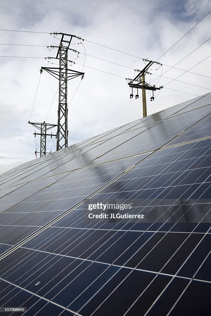 Electrical towers behind energy grid panels with sky