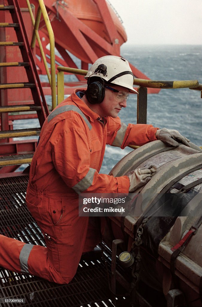 A man in safety gear working on a oil rig