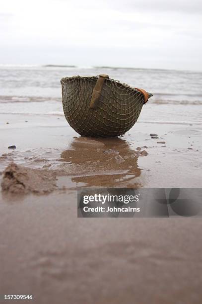 helmet on omaha beach. - omaha beach stock pictures, royalty-free photos & images