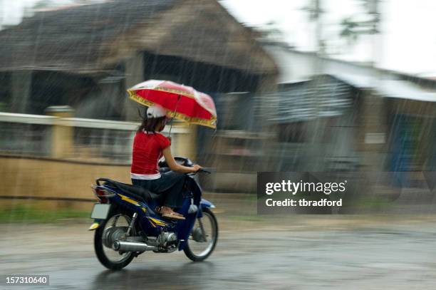 mujer joven montando una motocicleta mientras sostiene una sombrilla - vietnam teen fotografías e imágenes de stock