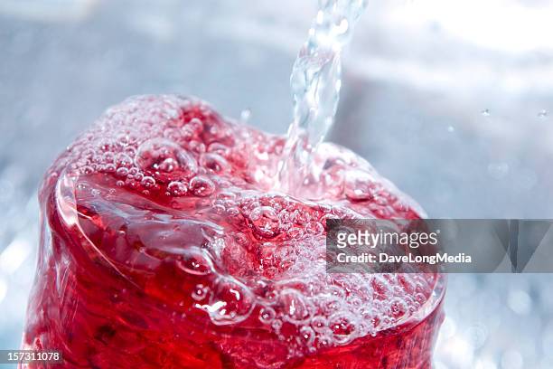 close-up of a bubbly red drink - overflowing glass stockfoto's en -beelden