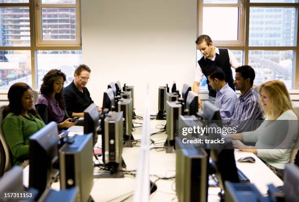 adult education: mature students working in a computer laboratory - computer lab classroom stock pictures, royalty-free photos & images