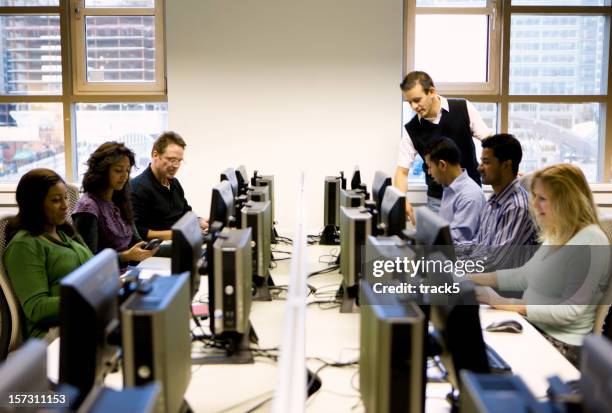 adult education: mature students working in a computer laboratory - computer lab stock pictures, royalty-free photos & images