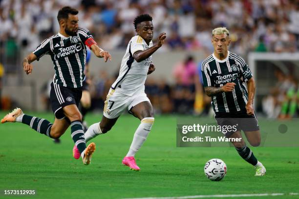 Vinicius Júnior of Real Madrid dribbles the ball between Bruno Fernandes of Manchester United and Lisandro Martinez in the first half during the 2023...