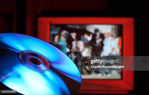 blu-ray dvd disc against red tv - blu raydisk stockfoto's en -beelden