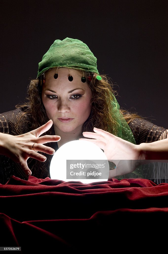 Fortune teller looking at glowing crystal ball