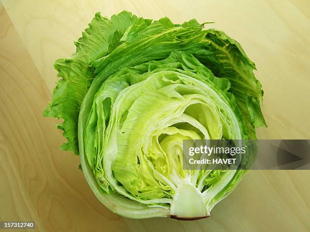 iceberg lettuce cut in half on wood surface - iceberg lettuce stock pictures, royalty-free photos & images