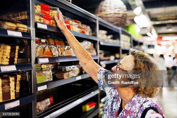 senior shopping in supermarket - reaching higher stock pictures, royalty-free photos & images