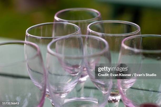 empty wine glasses on a green table outdoors - empty glasses after party stock-fotos und bilder