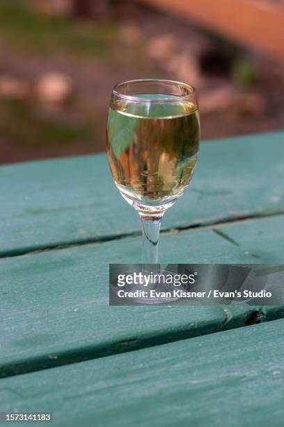 white wine glass on a green park bench table - evan kissner stock pictures, royalty-free photos & images