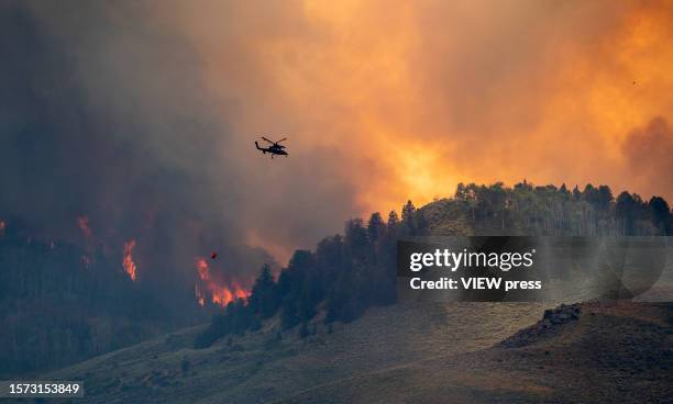 Chopper drops water as smoke billows and flames rise from the Lowline fire on July 26, 2023 near Gunnison, Colorado. The US Forest Service said the...