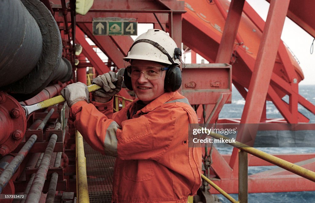 Man Dressed in Orange Working on an Oil Rig