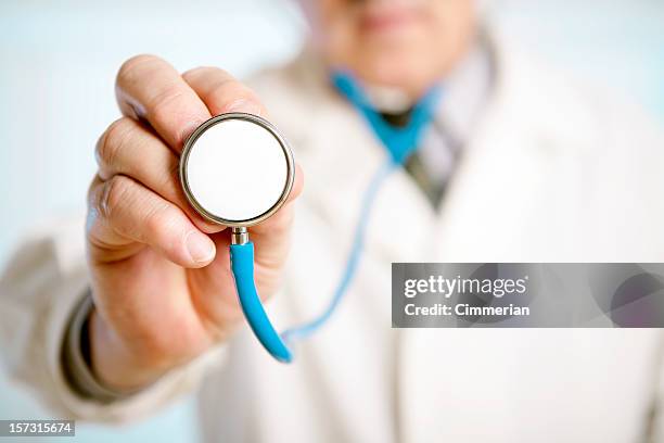 nahaufnahme von einem männlichen arzt hand hält ein stethoskop - kardiologe stock-fotos und bilder