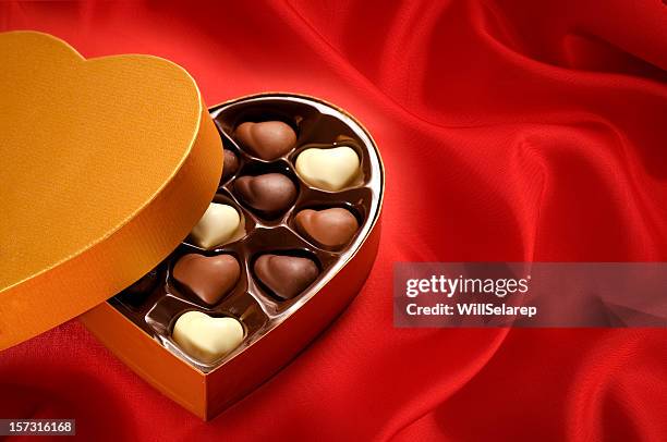 golden chocolates box on red satin background - chocolate box stockfoto's en -beelden