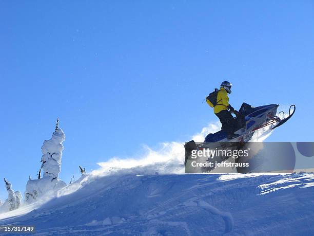 man on snowmobile jumping on hilltop - snow vehicle stock pictures, royalty-free photos & images