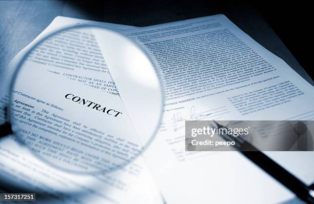 magnifying glass examining signed legal contract - overeenkomst stockfoto's en -beelden