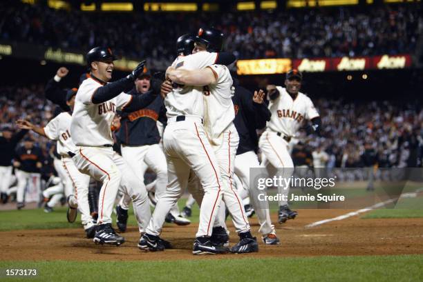 Third baseman David Bell of the San Francisco Giants hugs shortstop Rich Aurilia at home plate after scoring the game-winning run to end game five of...