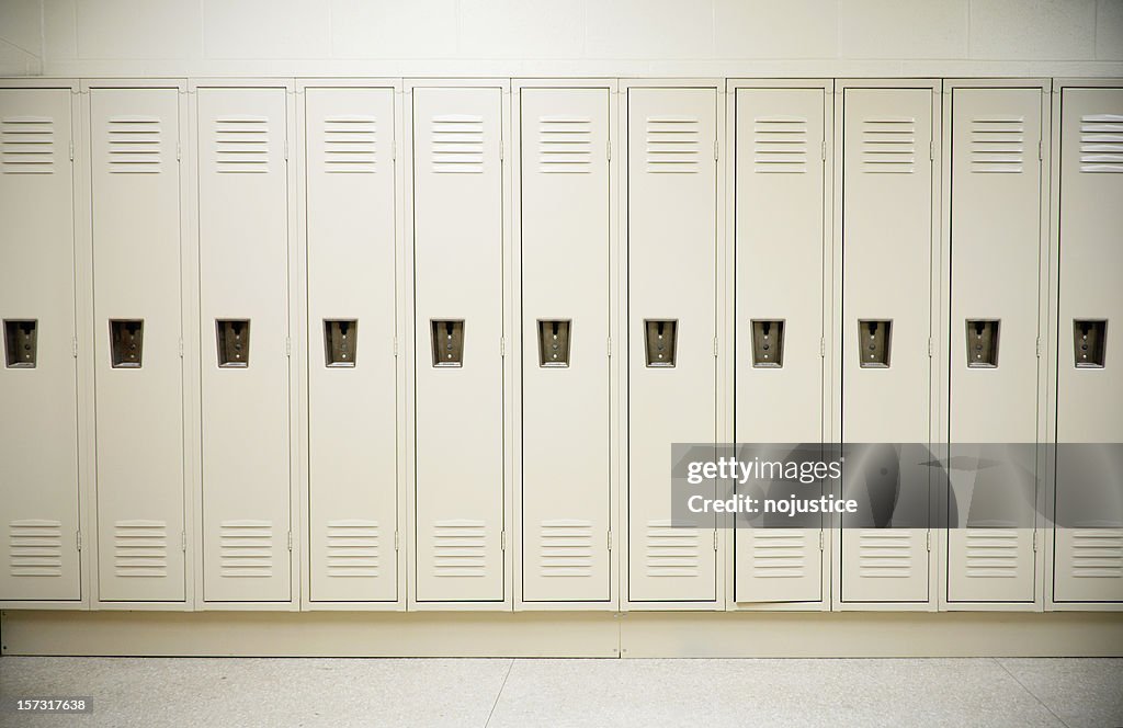 Row of tall white lockers in a white corridor