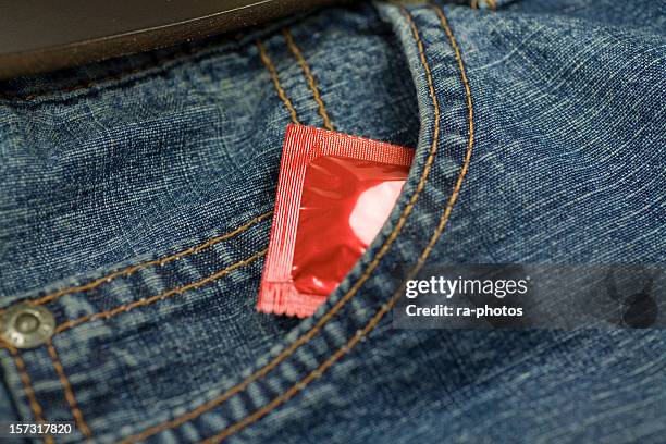 a condom sticking out of a jeans pocket - condooms stockfoto's en -beelden