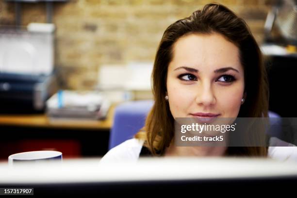 modern workplace: a contemporary creative professional at her desk - smirk stock pictures, royalty-free photos & images