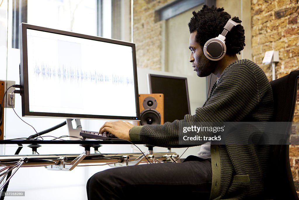 Modern workplace: sound editor at his desk editing wave forms