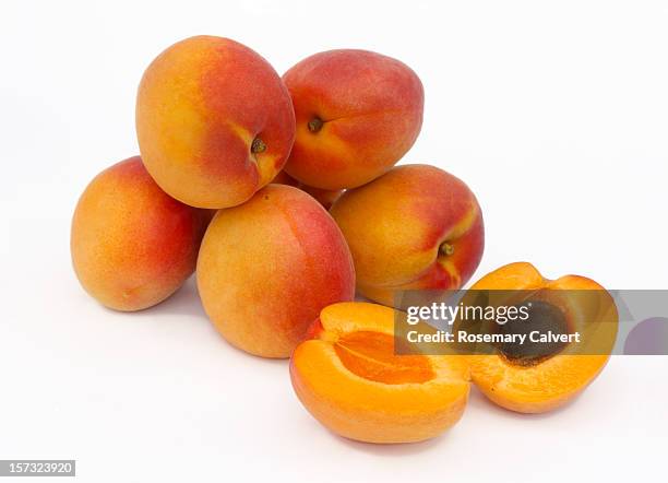 a pile of ripe apricots, one halved - albaricoque fotografías e imágenes de stock