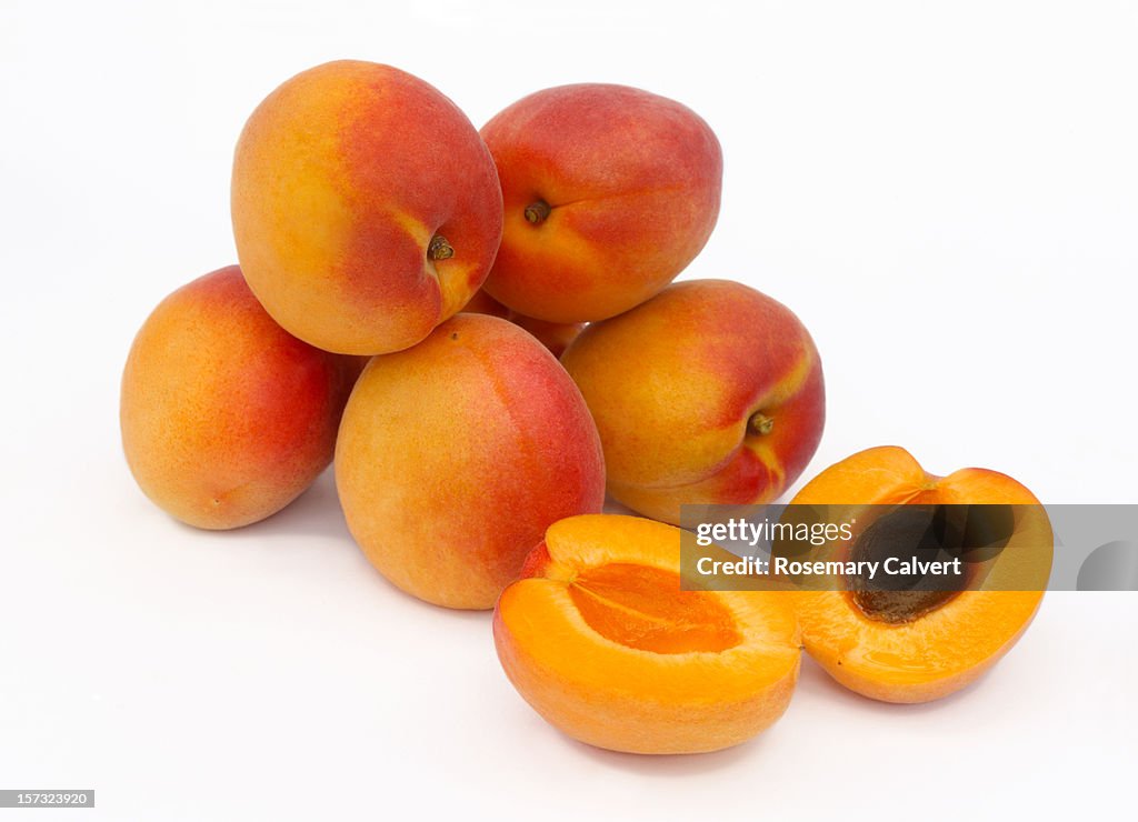 A pile of ripe apricots, one halved