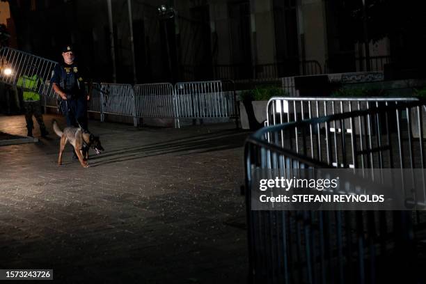 Police officer walks with a dog as workers set up security barricades outside the E. Barrett Prettyman US Courthouse in Washington, DC, on August 2...